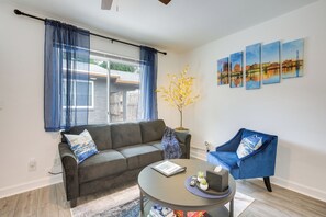 A living room with a grey sofa, a blue armchair, a round coffee table, and a potted plant.