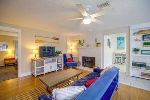 A living room with a sofa, a television, a ceiling fan, and a fireplace. - Pool Access, Walk to Beach! Cape Canaveral Apt (Cape Canaveral)
