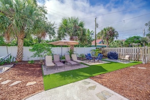 A backyard with artificial grass, a patio area with chairs and a table, and a wooden fence. - Pool Access, Walk to Beach! Cape Canaveral Apt (Cape Canaveral)