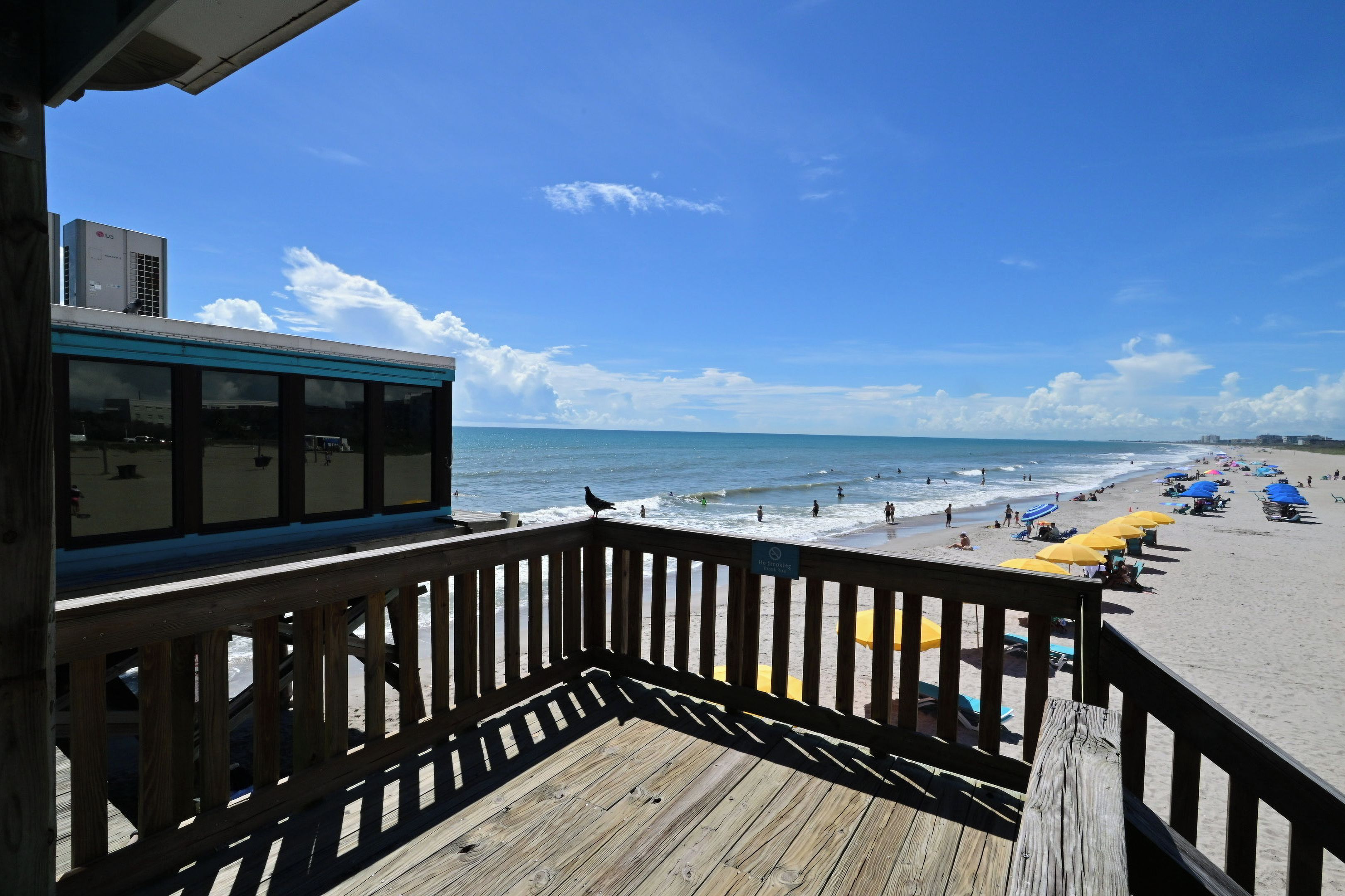 A wooden deck with a view of the beach and ocean.