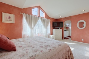 Ein Schlafzimmer mit einem Bett, einem Schminktisch, einem Spiegel und einem Fenster mit Vorhängen.