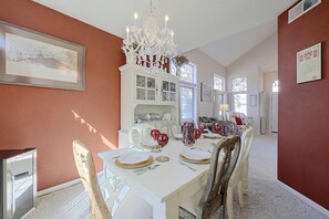 A dining room with a white table set for four, a chandelier, and a cabinet with glass doors. - San Jose Furnished Stay w/ Laundry (San Jose)