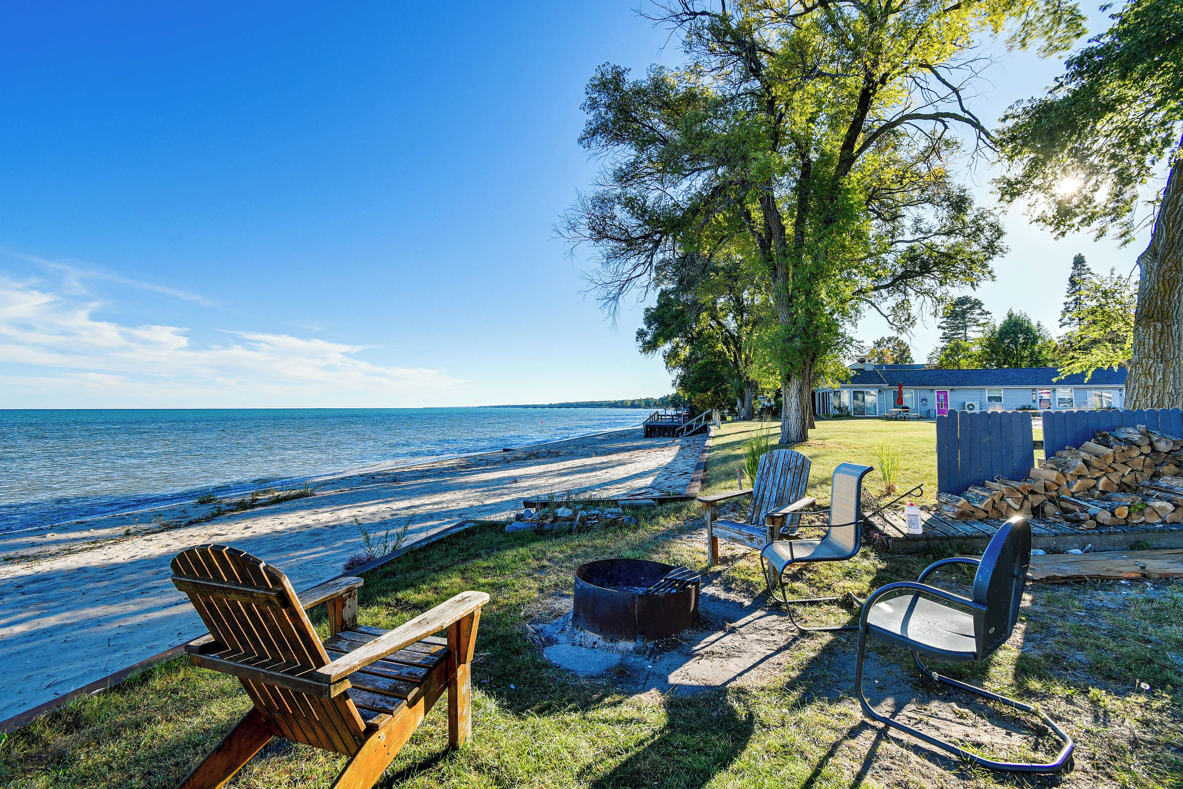 A lakeside property with a wooden deck, outdoor seating, and a view of the water.