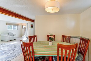 A dining area with a round table, chairs, a striped tablecloth, and a potted plant. - Steps to Bay! Home w/ Hot Tub in Tawas City (Tawas City)