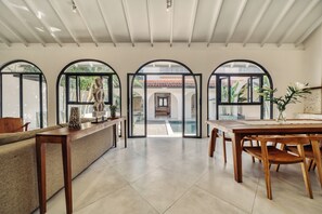 Ein geräumiger Raum mit Essbereich, einer Rezeption und Blick auf ein Schwimmbad durch Bogenfenster.
