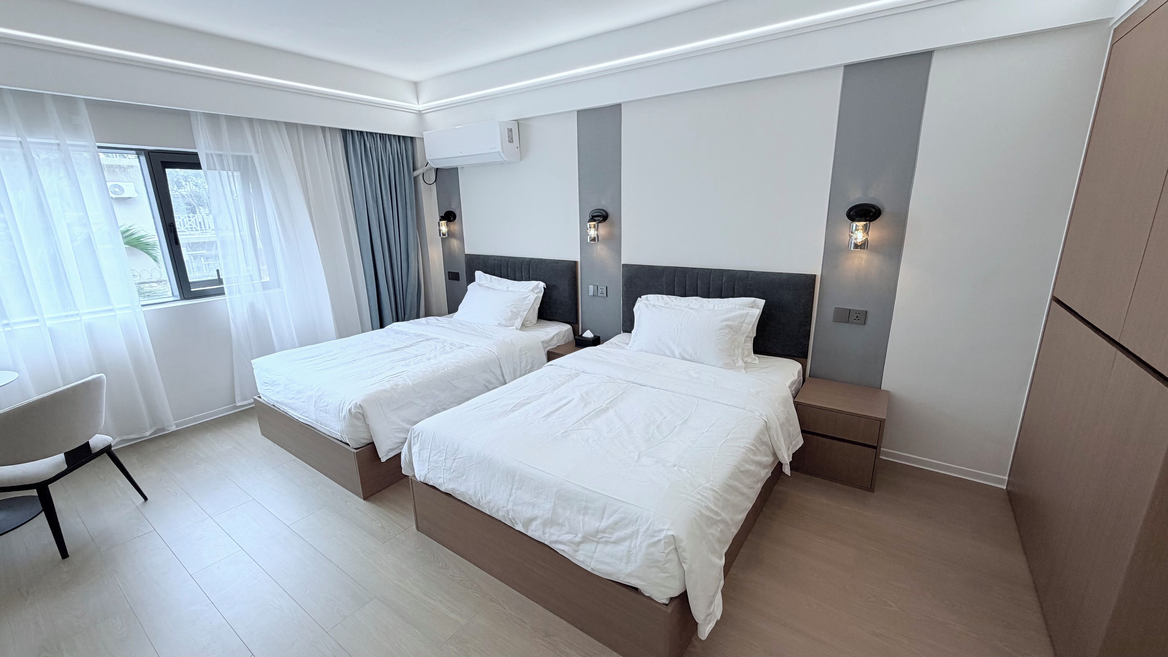 A hotel room with two beds, a desk, and a chair.