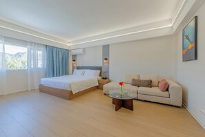 Una habitación de hotel moderna con una cama, un sofá, una mesita de café y un cuadro en la pared.