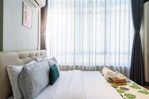 A hotel room with a bed, pillows, a blanket, a wall-mounted air conditioner, and a window with curtains. - Forbestown BGC |Luxury 2BR loft| Pool & Gym Use (Taguig)