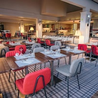 Ein Restaurant mit mehreren Tischen und Stühlen, einem Schachbrettmuster Boden und einem sichtbaren Küchenbereich.