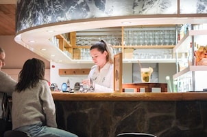 A bar area with a counter, glasses, and a person serving.