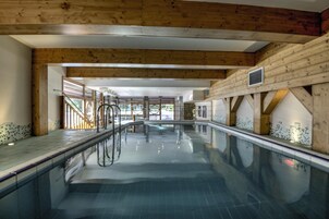 Ein Innenpool mit Holzbalken und gefliesten Wänden.