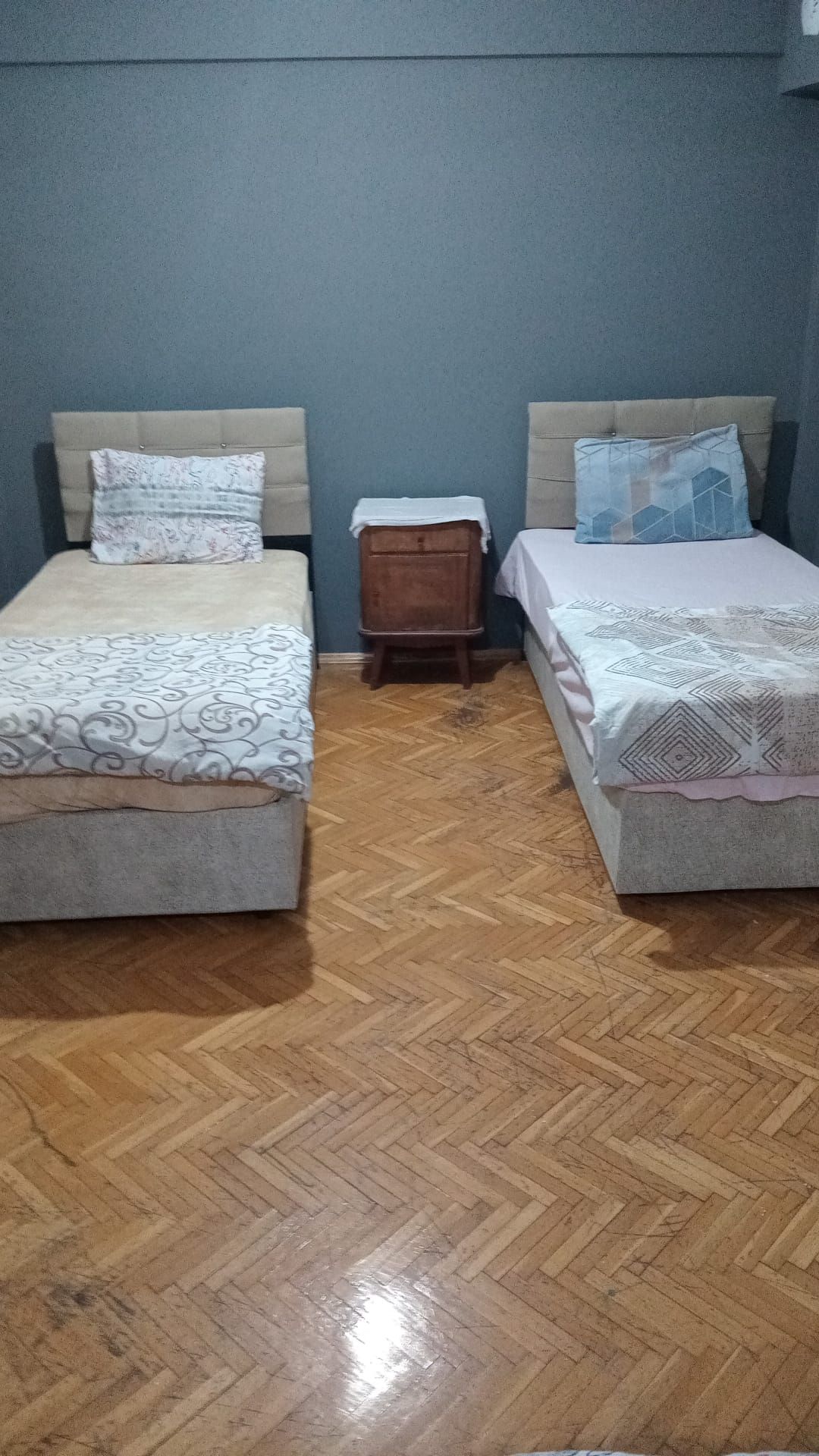 Habitació amb dos llits, una petita nitlínia de fusta i un paviment amb dibuix de guillotes.
