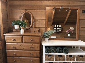 A wooden vanity with a mirror, a plant, and a shelf with rolled towels. - Resort-style Executive and Family Retreat (Hornsby)