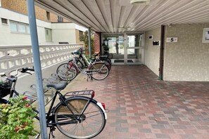 A covered outdoor area with a brick floor, bicycles parked, and a building entrance with a number sign. - Holiday apartment with 1 bedroom (Westerland)