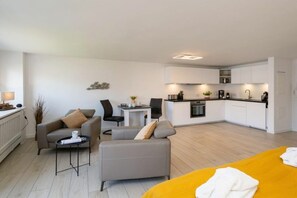 A modern apartment with a living area, a dining table, a kitchen, and a bed. - Holiday apartment with 1 bedroom (Westerland)