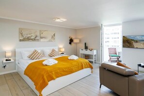 A hotel room with a large bed, a desk, a chair, and artwork on the walls. - Holiday apartment with 1 bedroom (Westerland)