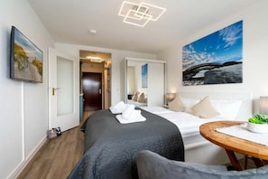Ein Hotelzimmer mit einem Bett, einem Nachttisch mit Pflanze, einem großen Fenster mit Brückenblick und einem Gemälde an der Wand.