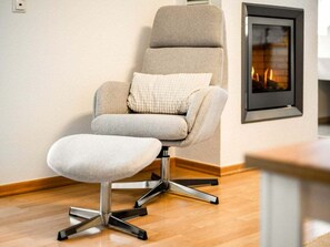 Ein moderner Sessel mit Fußstütze und Polsterung, ein Kamin und ein Holzboden.