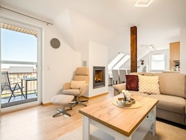 Uma sala de estar moderna com sofá, poltrona e uma mesa com um objeto decorativo.