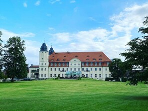 A large, historic building with a central tower and multiple windows, surrounded by a well-maintained lawn. - Longest Drive Upper Floor (Goehren-Lebbin)