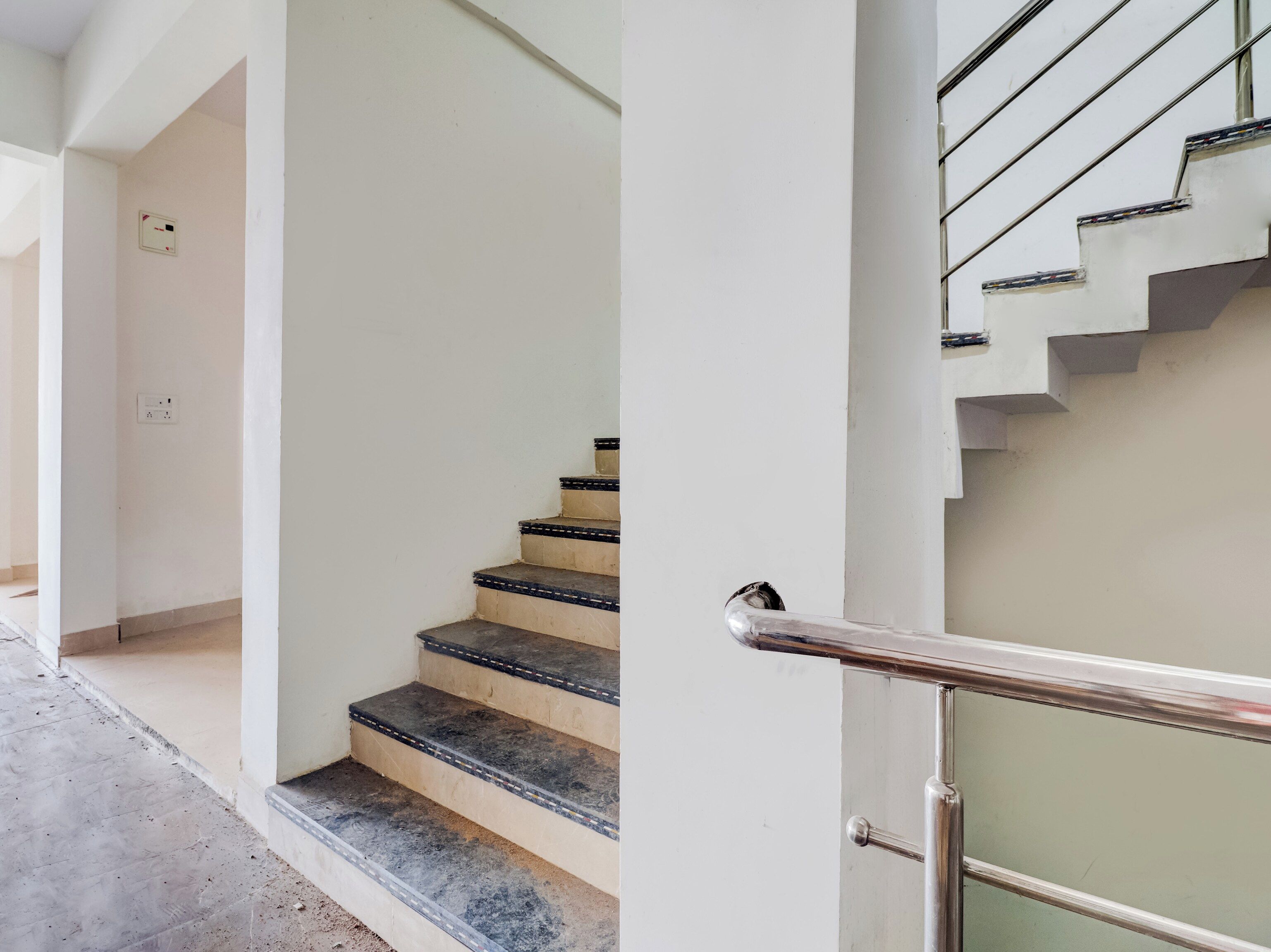 Una escalera con barandilla de metal y peldaños color beige.
