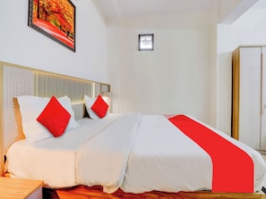 Une chambre d’hôtel comprenant un lit, une table de chevet, une commode, une fenêtre et une armoire.