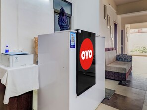 Une pièce comprenant un réfrigérateur orné d’un logo rouge, un canapé et une table sur laquelle se trouve une bouteille d’eau.