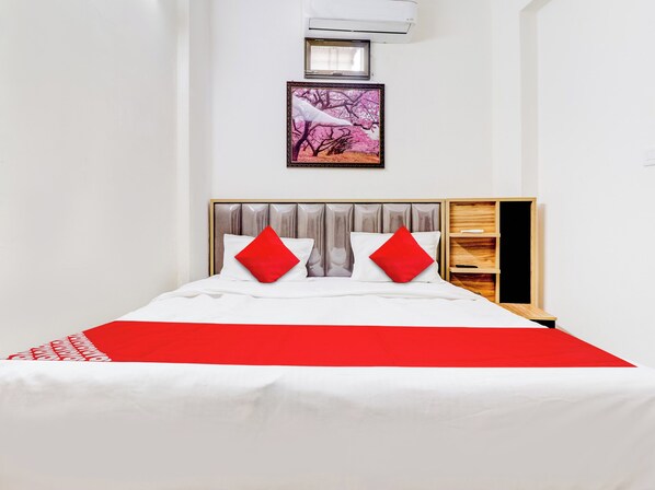 A bed with a white and red bedspread, two red pillows, and a wooden headboard.