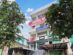 A multi-story building with a prominent 'HOTEL RA' sign, a 'Top N Towns' sign, and a 'OYO' branded entrance.
