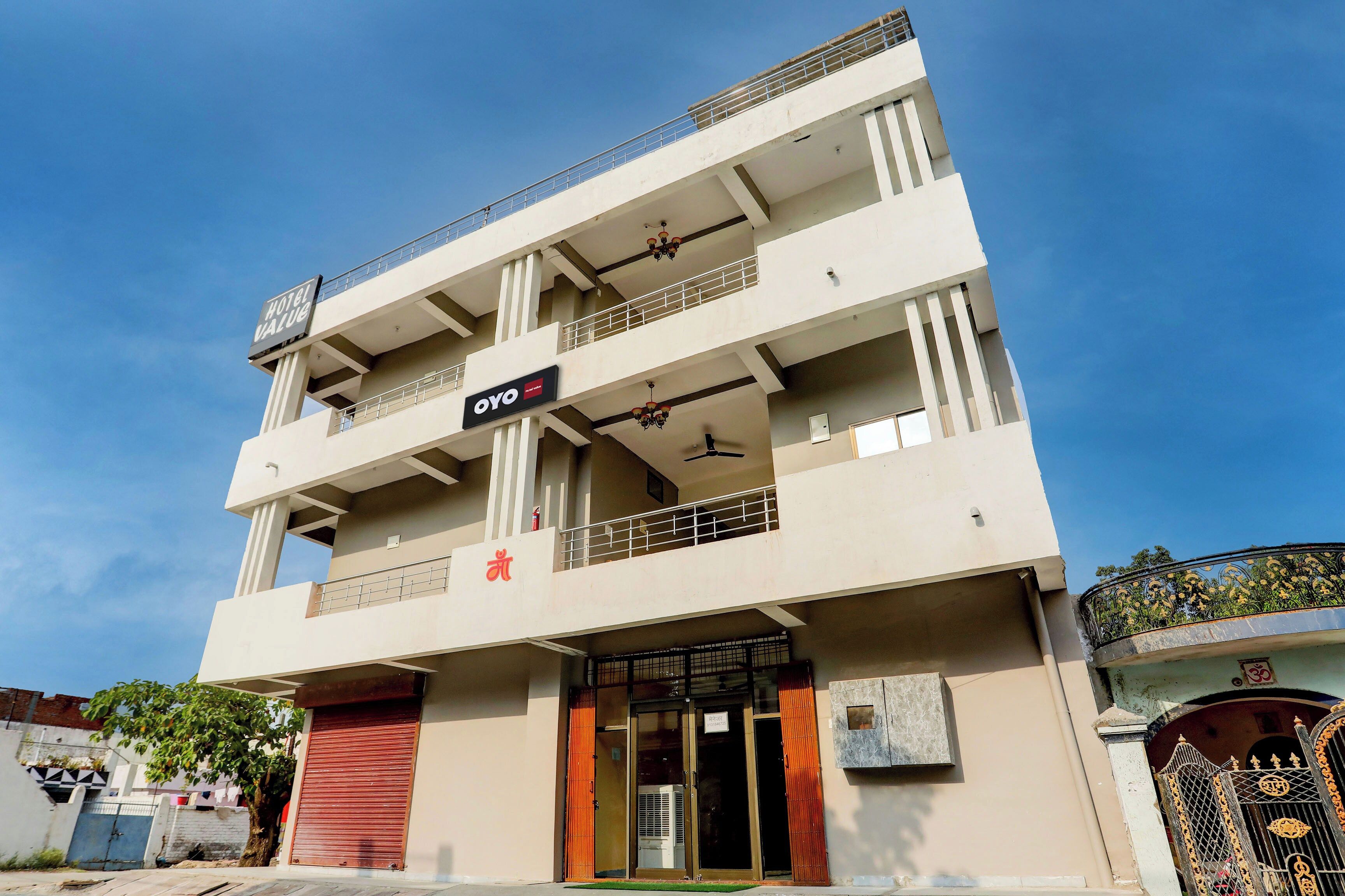 A multi-story building with a sign for 'Hotel Value' and 'OYO' indicating a hotel and a restaurant.