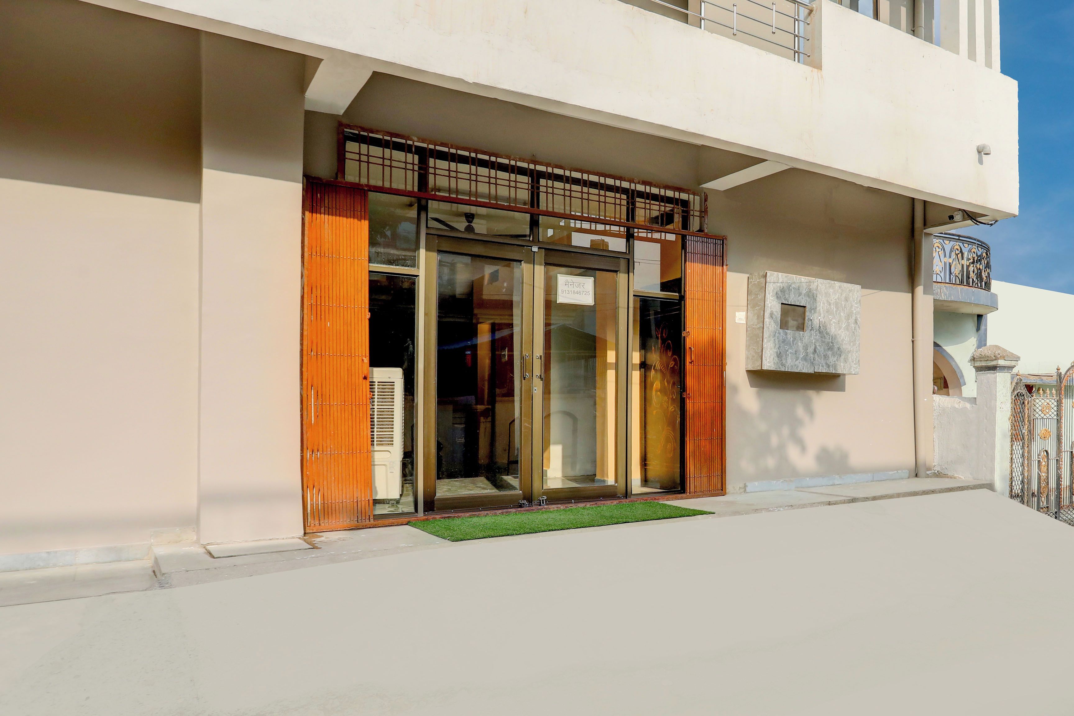 A building with a gated entrance, a small outdoor area with a mat, and a balcony with a railing.