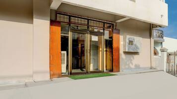 A building with a gated entrance, a small outdoor area with a mat, and a balcony with a railing.