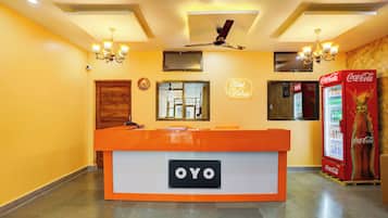 Un comptoir d’accueil avec une enseigne indiquant « OYO » et un réfrigérateur Coca-Cola.