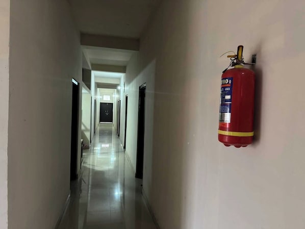 A corridor with a fire extinguisher mounted on the wall. - Hotel O CityMax (Jabalpur)