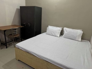 Une chambre avec un lit, un bureau en bois et une armoire.