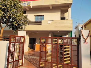 A gated entrance to a residential building with a balcony and a tree in the foreground. - Hotel O CityMax (Jabalpur)