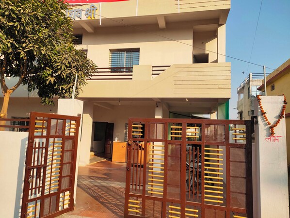 A gated entrance to a residential building with a balcony and a tree in the foreground.
