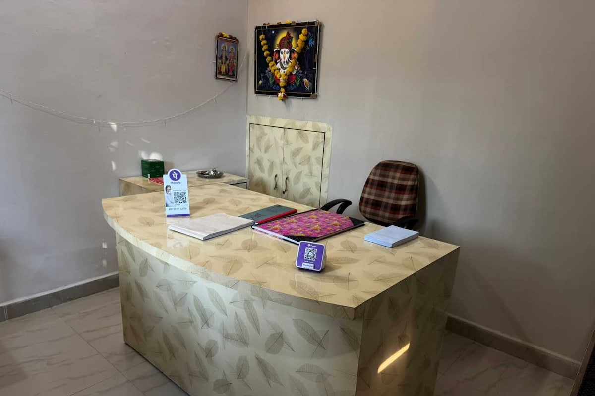 Un comptoir d’accueil au motif décoratif, un tableau encadré au-dessus, et une chaise sur la droite.