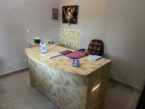 Un comptoir d’accueil au motif décoratif, un tableau encadré au-dessus, et une chaise sur la droite.