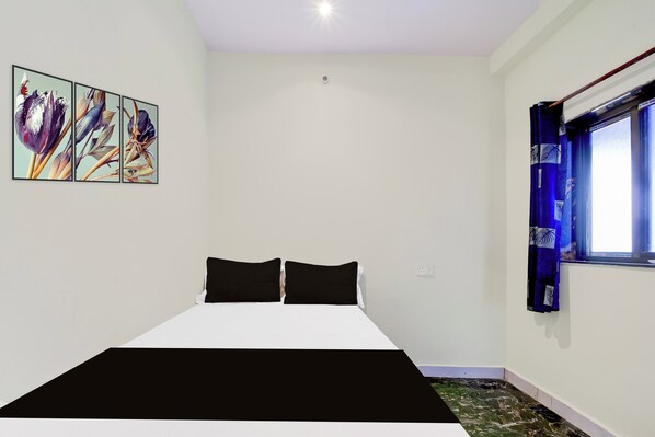 Un dormitorio con cama, ropa de cama blanco y negro, una ventana con cortinas y una obra de arte colgada en la pared.