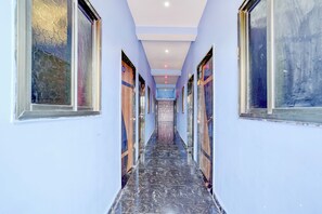 A corridor with a marble floor and large windows on both sides. - Hotel O by OYO Virashat (Sihora)