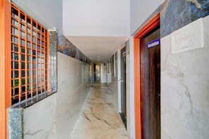 A corridor with marble flooring, a reception area, and a window with a metal grille.
