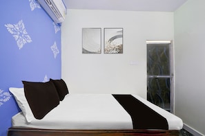 Une pièce comprenant un lit, deux œuvres d’art accrochées au mur, une porte et un appareil de climatisation.