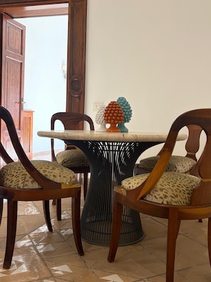 A dining area with a round table, four wooden chairs with leopard print cushions, and a decorative tree sculpture on the table. - New Listing (Roma)