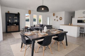 A modern kitchen with white cabinets, a built-in oven, and a dining area with a dark wooden table and black chairs. - New Listing (Roujan)