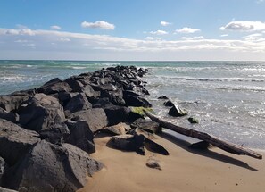 A rocky shoreline with waves crashing onto the sand. - New Listing (Roujan)