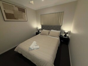 A hotel room with a large bed, two bedside tables, a headboard, and a framed picture on the wall. - Luxurious family home away from home, comfortable (Park Ridge)