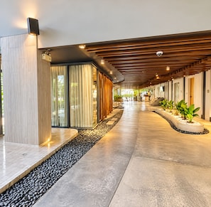 A modern hotel corridor with a wooden ceiling, a reception desk, and a seating area with plants. - Private and Direct access to the beach in Pattaya Jomtien (Pattaya Jomtien)