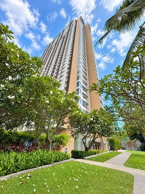 A high-rise building with a modern design, surrounded by well-maintained greenery and a clear sky. - Prime Location Apartment in Pattaya Jomtien (ตำบล หนองปรือ)