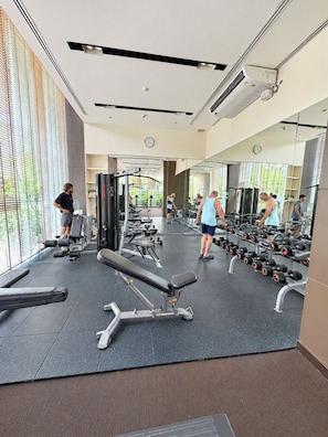A gym with exercise equipment, mirrors, and a water dispenser. - Prime Location Apartment in Pattaya Jomtien (ตำบล หนองปรือ)